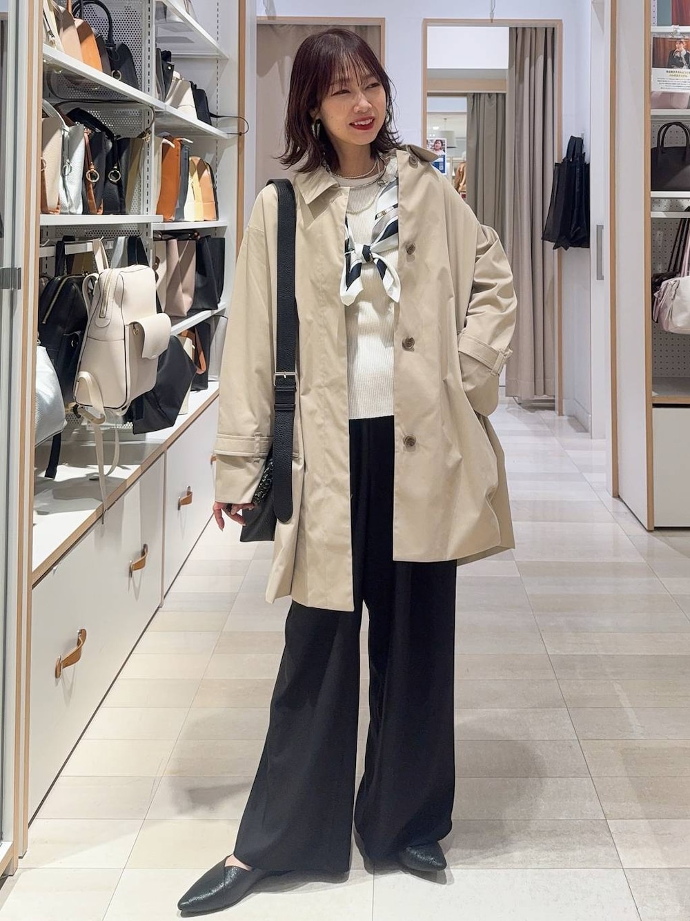 ブラック系のパンプス、ベージュ系のステンカラーコート、ブラック系のその他パンツを着用したレディースの春コーディネートの1枚目の写真