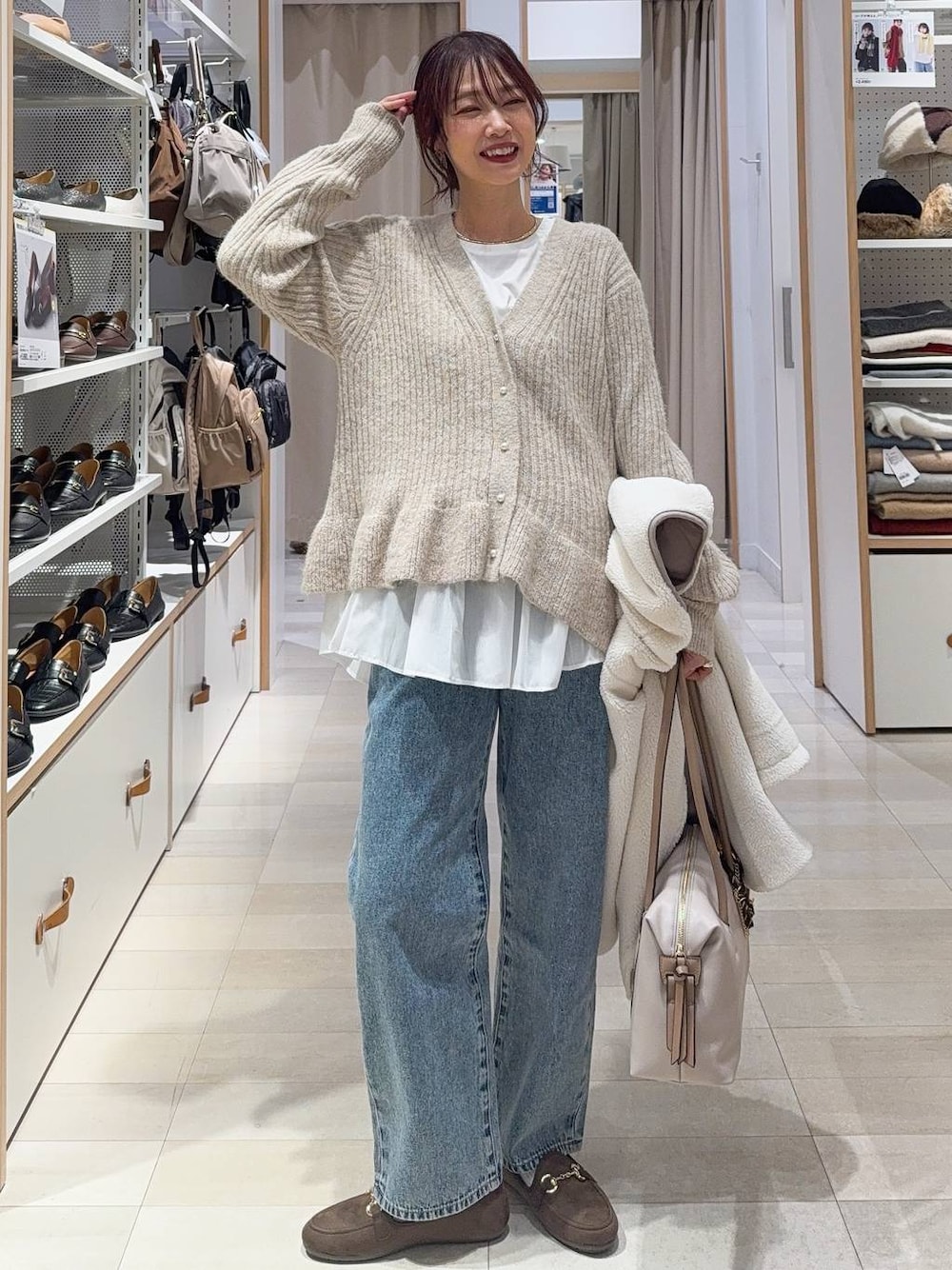 ホワイト系のボストンバッグ、ホワイト系のブルゾン、ブルー系のデニムパンツを着用したレディースの秋コーディネートの1枚目の写真
