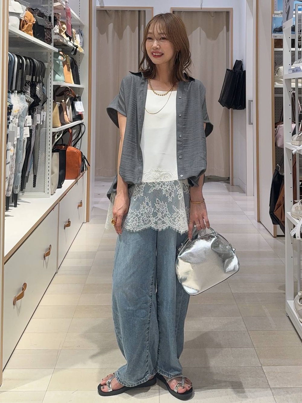 シルバー系のショルダーバッグ、ブルー系のデニムパンツ、ホワイト系のキャミソールを着用したレディースの夏コーディネートの1枚目の写真
