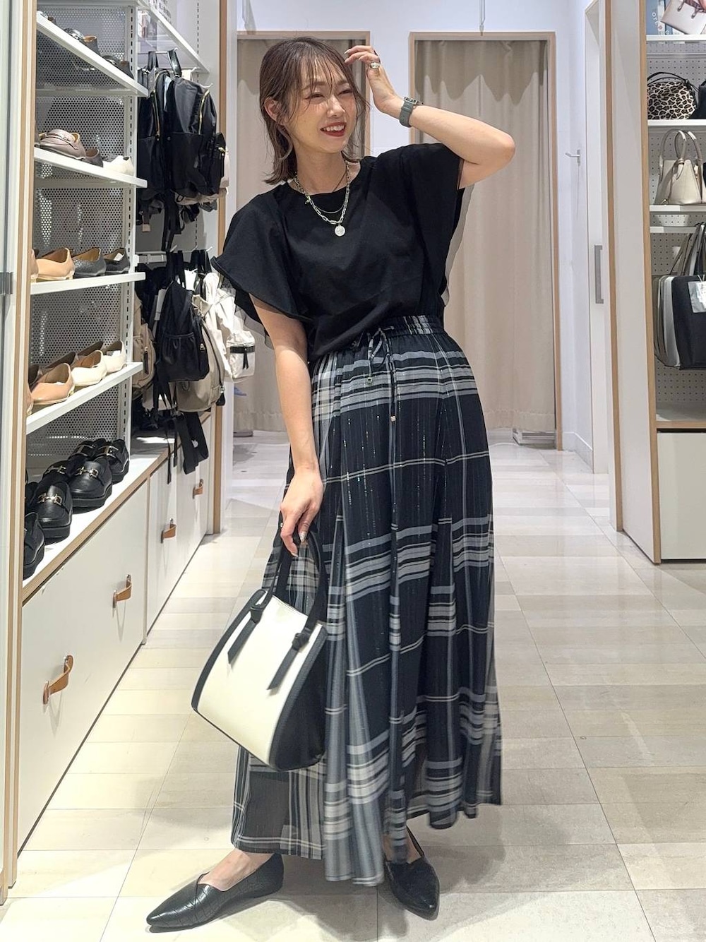 ブルー系のスカート、ホワイト系のショルダーバッグ、ブラック系のTシャツ/カットソーを着用したレディースの夏コーディネートの1枚目の写真