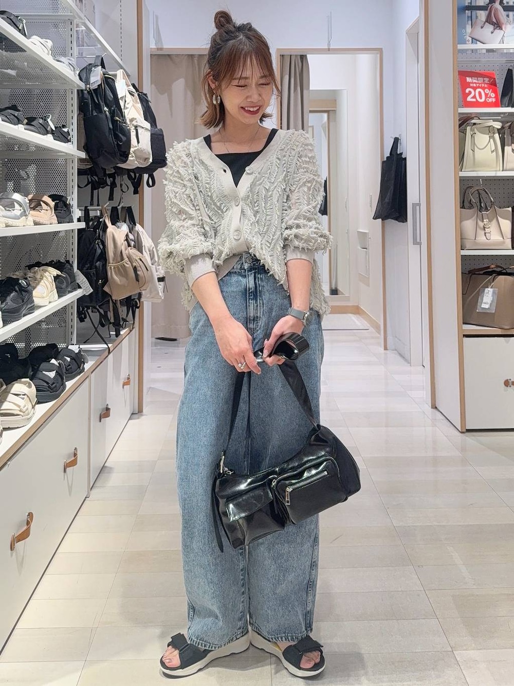 ブルー系のデニムパンツ、ブラック系のショルダーバッグ、ブラック系のタンクトップを着用したレディースの春コーディネートの1枚目の写真