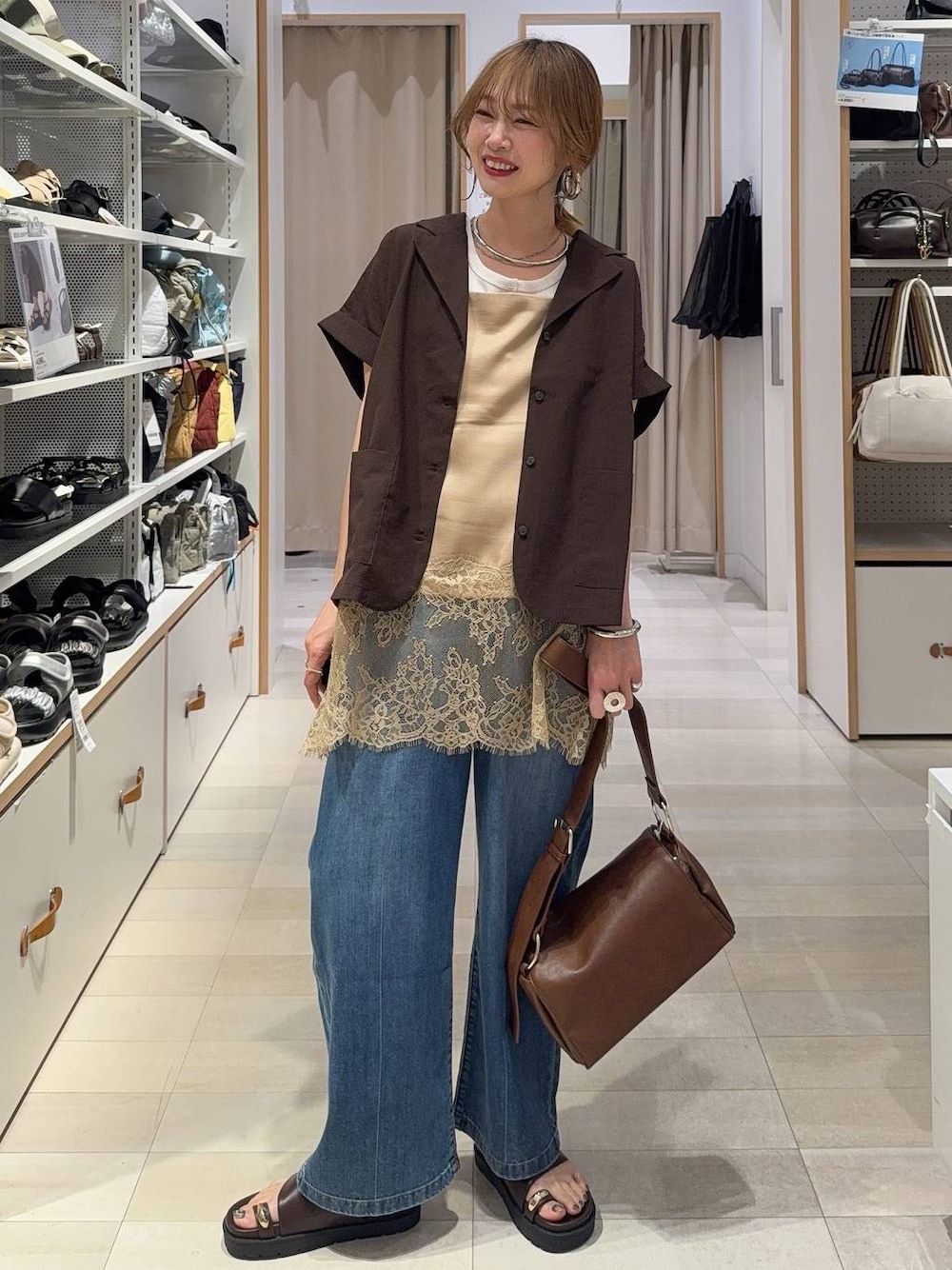 ブルー系のデニムパンツ、ホワイト系のタンクトップ、ブラウン系のシャツ/ブラウスを着用したレディースの春コーディネートの1枚目の写真