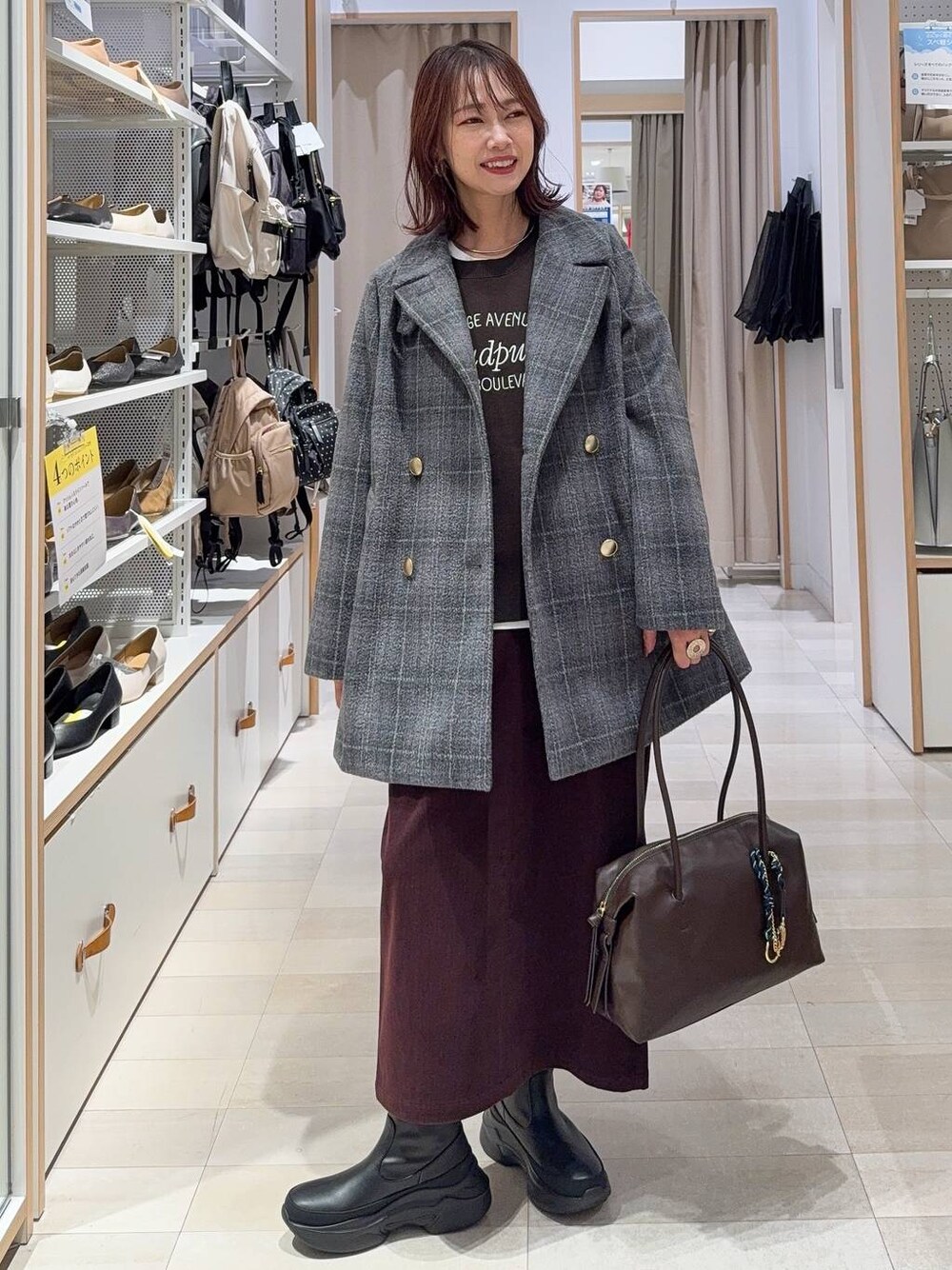 ブラウン系のボストンバッグ、グレー系のチェスターコート、レッド系のスカートを着用したレディースの秋コーディネートの1枚目の写真