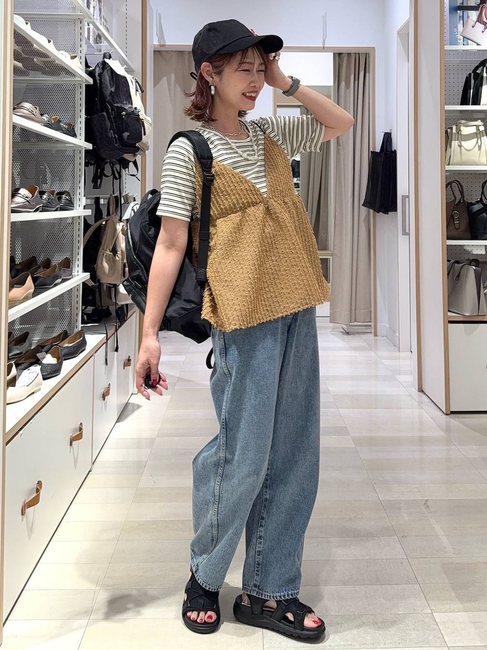 ブルー系のデニムパンツ、ブラック系のバックパック/リュック、ホワイト系のTシャツ/カットソーを着用したレディースの夏コーディネートの1枚目の写真