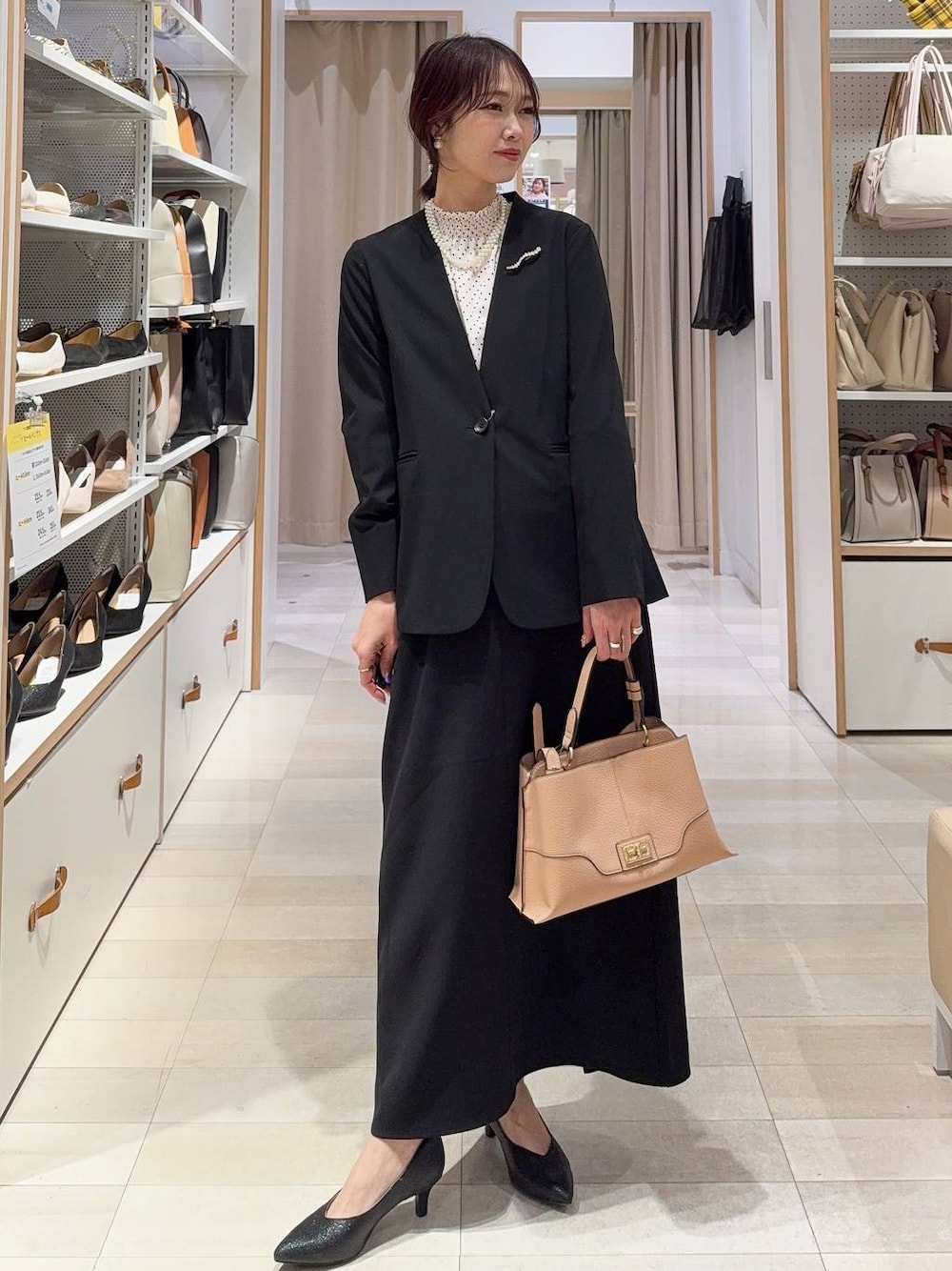 ブラック系のパンプス、ブラック系のノーカラージャケット、ベージュ系のショルダーバッグを着用したレディースの冬コーディネートの1枚目の写真