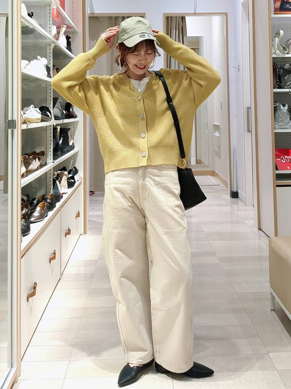 ベージュ系のデニムパンツ、ブラック系のショルダーバッグ、イエロー系のカーディガン/ボレロを着用したレディースの春コーディネートの1枚目の写真