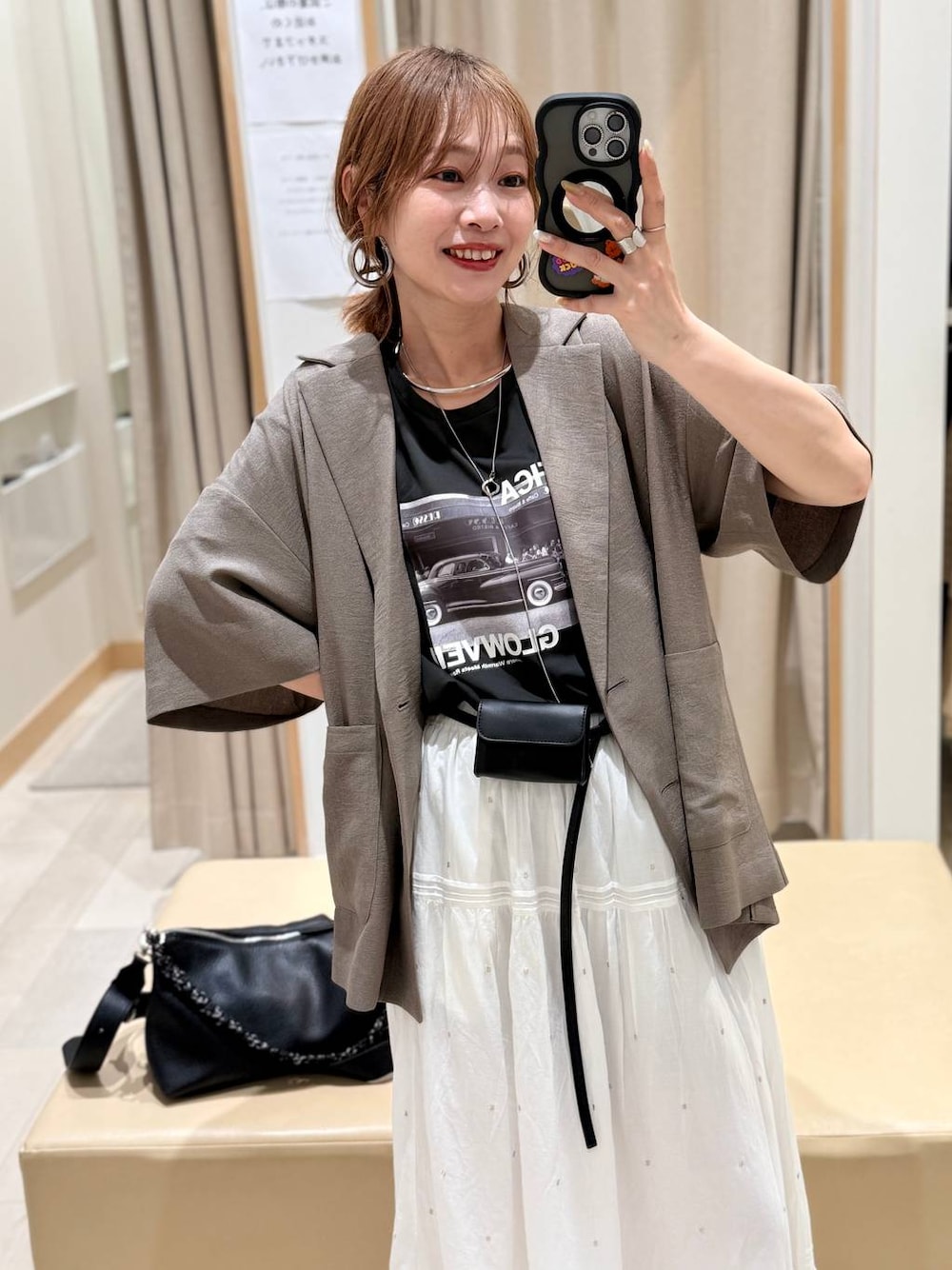 ホワイト系のスカート、ブラウン系のテーラードジャケット、グレー系のTシャツ/カットソーを着用したレディースの春コーディネートの1枚目の写真