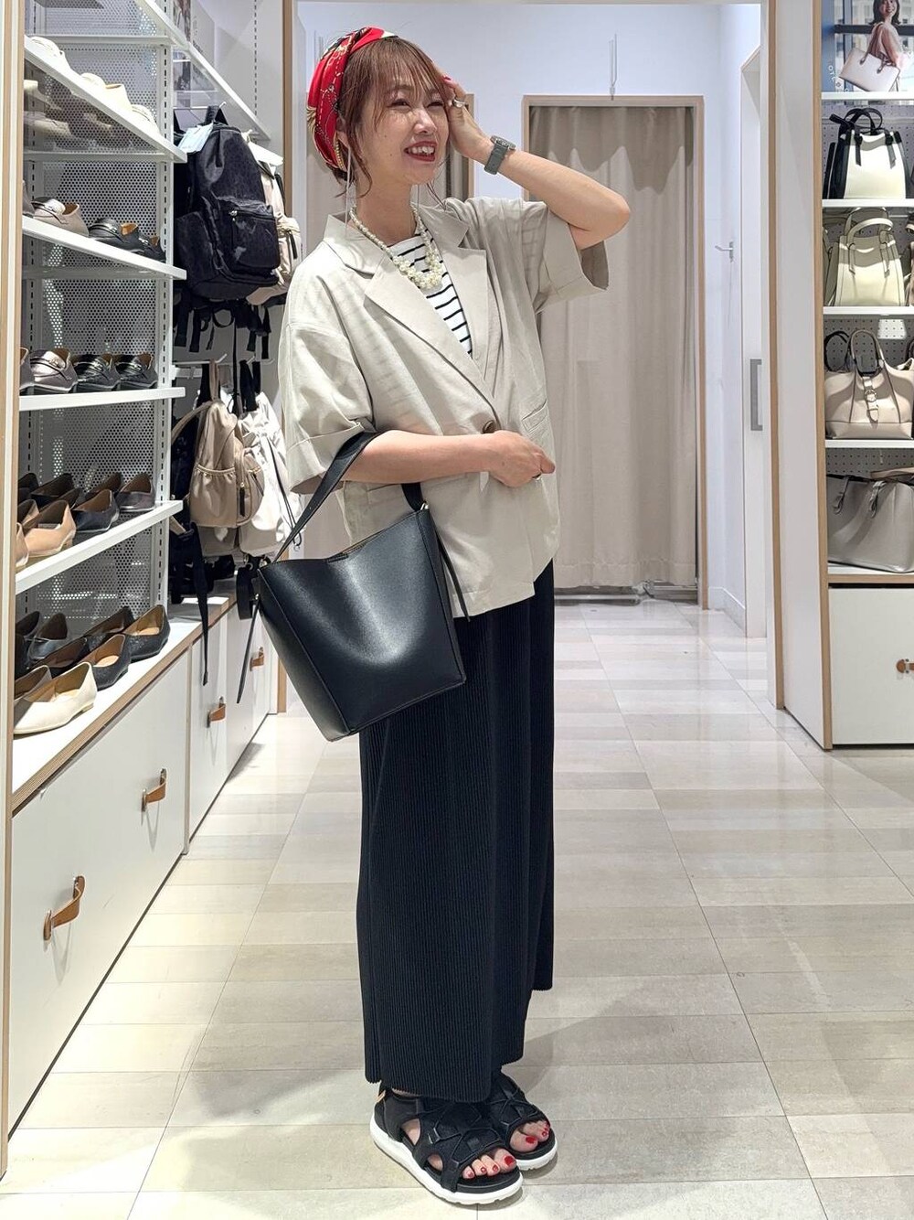 ブラック系のショルダーバッグ、ブラック系のスカート、ブラック系のサンダルを着用したレディースの夏コーディネートの1枚目の写真