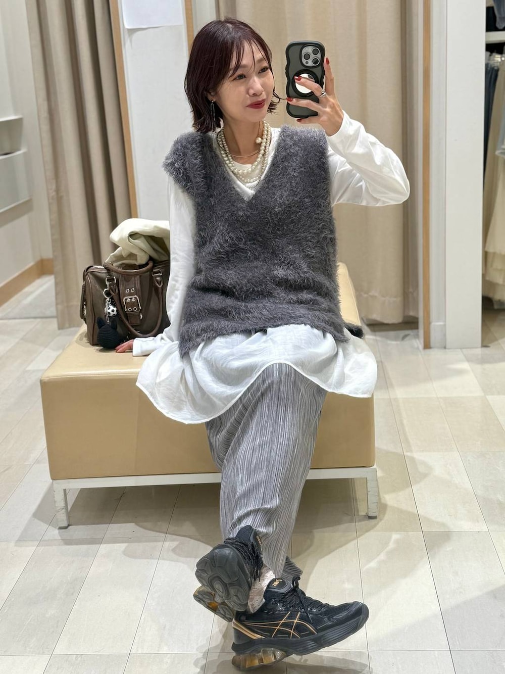 グリーン系のボストンバッグ、ホワイト系のブルゾン、グレー系のスカートを着用したレディースの秋コーディネートの1枚目の写真