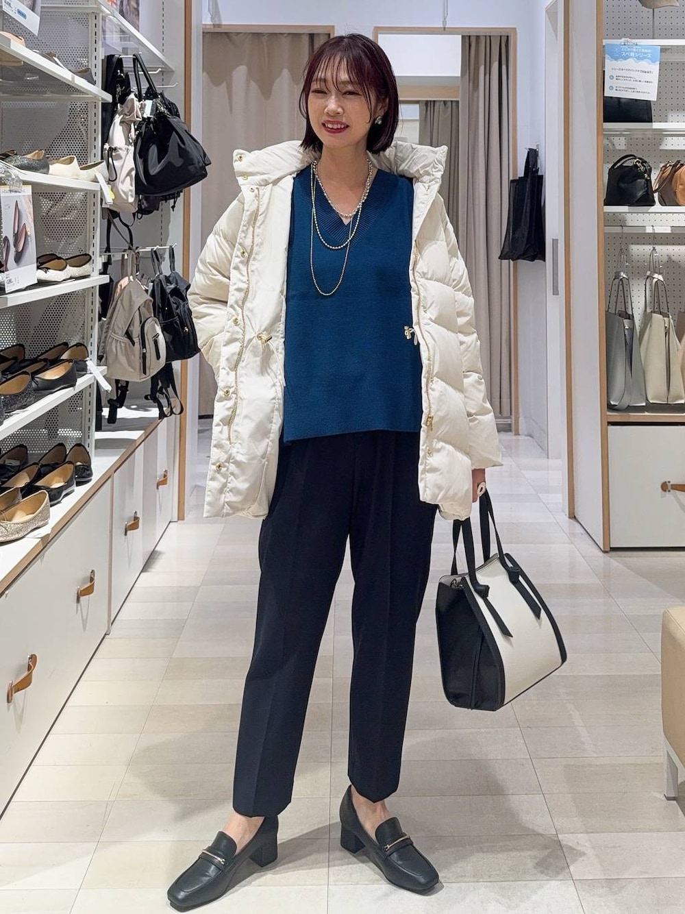 ブラック系のローファー、ホワイト系のショルダーバッグ、ベージュ系のダウンジャケット/コートを着用したレディースの秋コーディネートの1枚目の写真