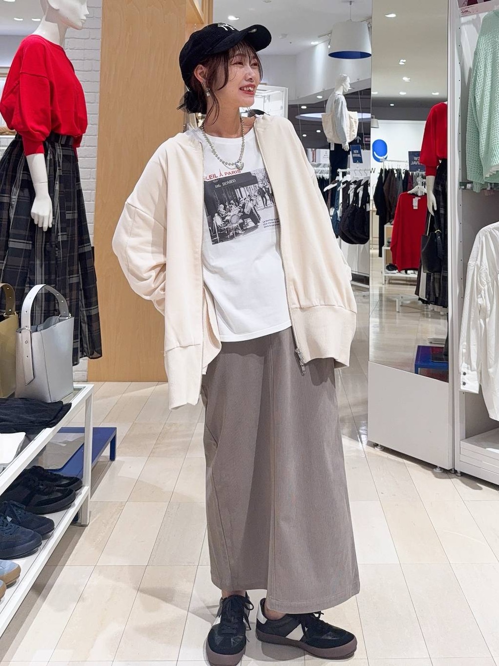 ブラック系のスニーカー、ブラウン系のスカート、ホワイト系のTシャツ/カットソーを着用したレディースの秋コーディネートの1枚目の写真