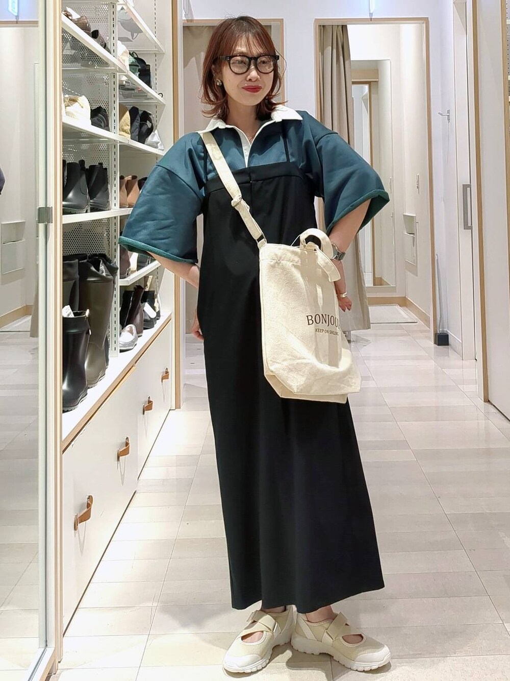 ホワイト系のスニーカー、ブラック系のワンピース、グリーン系のTシャツ/カットソーを着用したレディースの春コーディネートの1枚目の写真