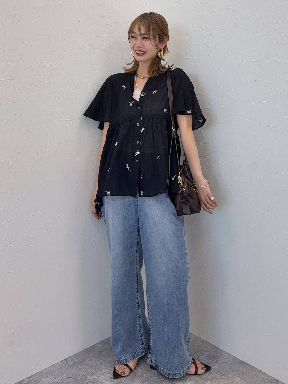 ブルー系のデニムパンツ、ブラウン系のボストンバッグ、ブラウン系のサンダルを着用したレディースの夏コーディネートの1枚目の写真