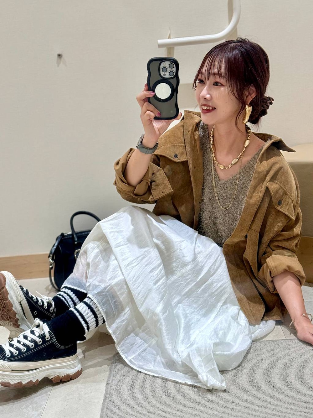 イエロー系のシャツ/ブラウス、ベージュ系のスカート、ブラック系のボストンバッグを着用したレディースの秋コーディネートの1枚目の写真