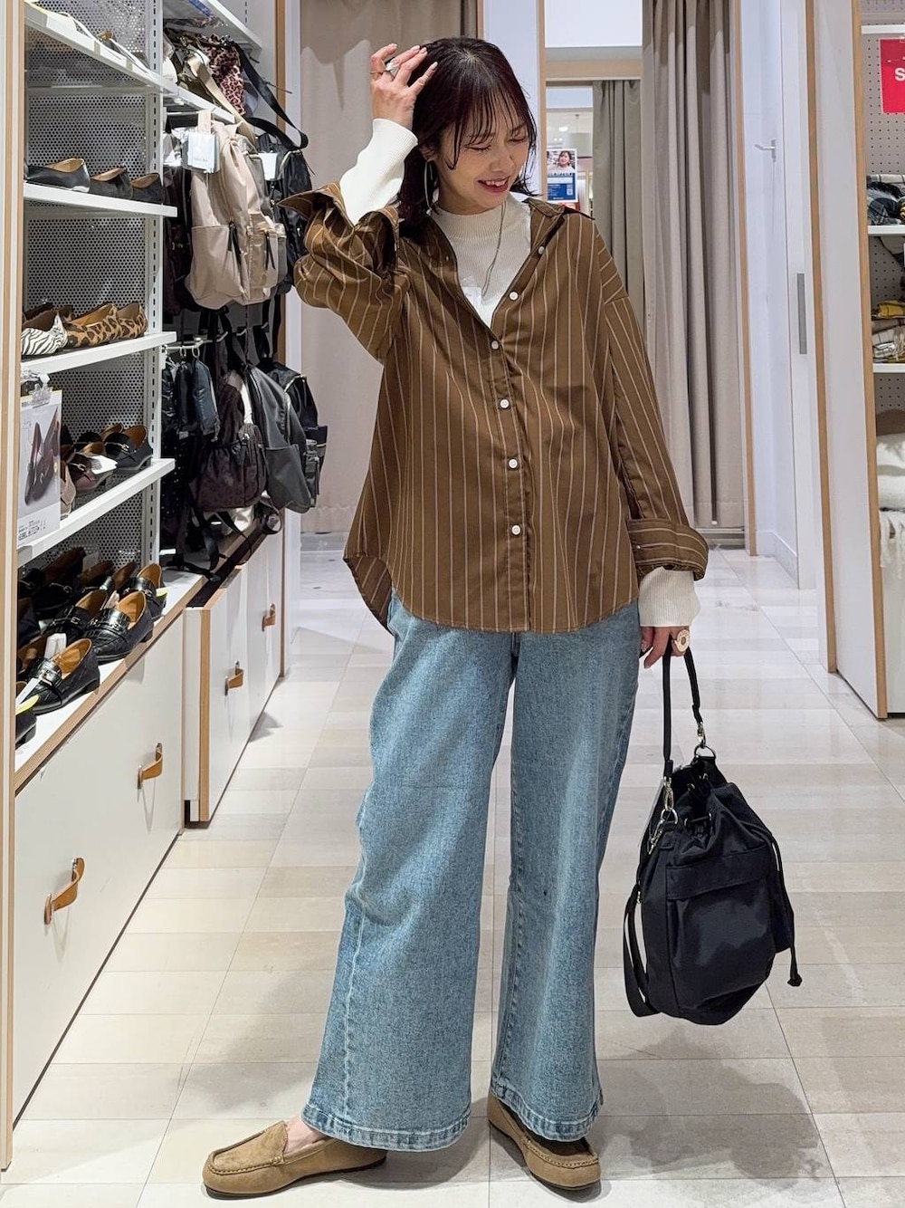 ブラック系のショルダーバッグ、ブルー系のデニムパンツ、ホワイト系のニット/セーターを着用したレディースの春コーディネートの1枚目の写真