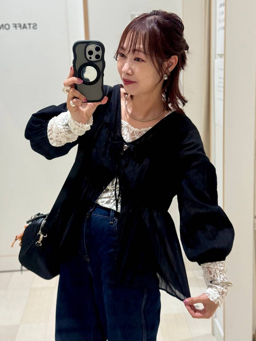 ブルー系のデニムパンツ、ブラック系のボストンバッグ、ブラック系のシャツ/ブラウスを着用したレディースの秋コーディネートの1枚目の写真