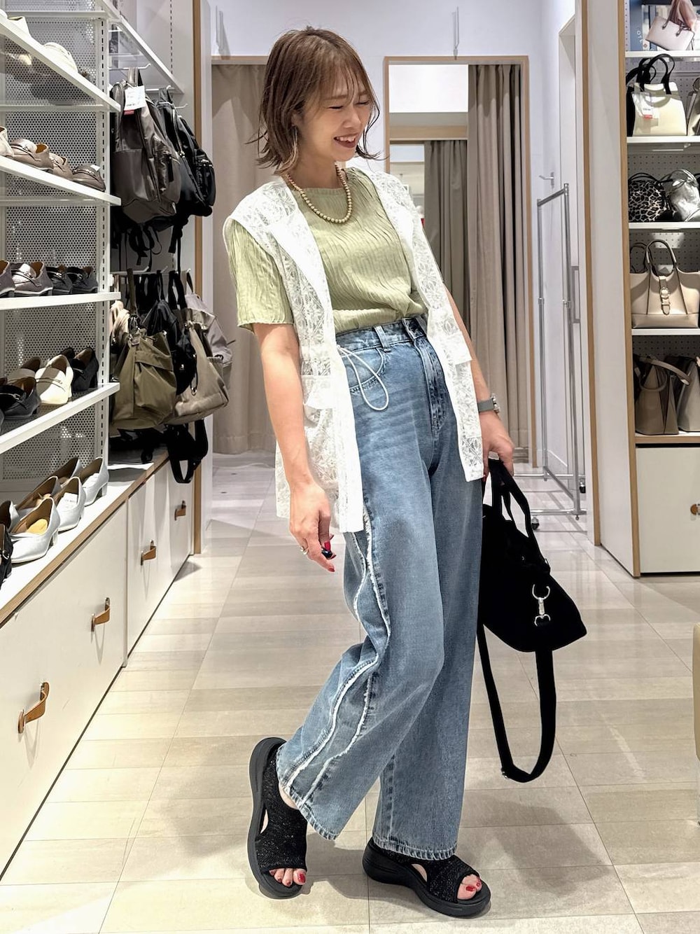 ブルー系のデニムパンツ、ブラック系のトートバッグ、グリーン系のTシャツ/カットソーを着用したレディースの春コーディネートの1枚目の写真