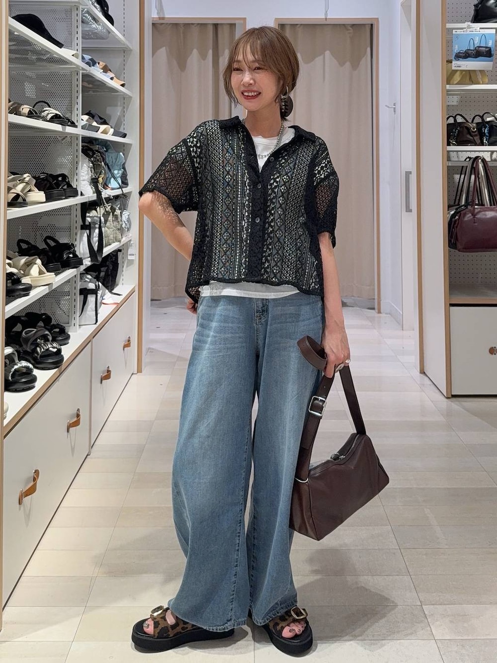 ブルー系のデニムパンツ、ブラウン系のショルダーバッグ、その他のサンダルを着用したレディースの夏コーディネートの1枚目の写真