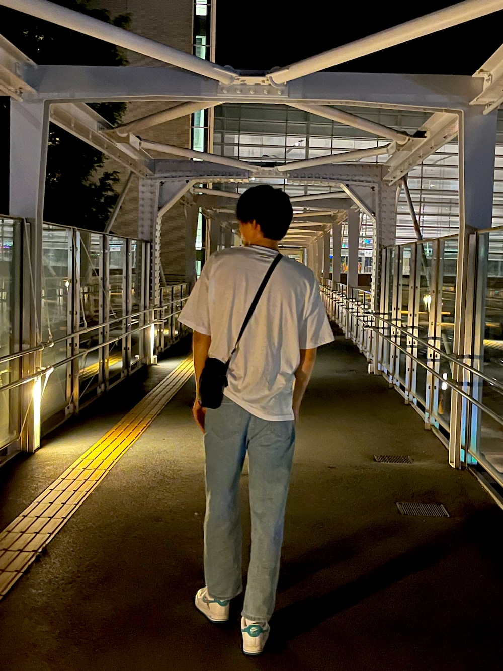 ホワイト系のTシャツ/カットソー、ブルー系のデニムパンツ、ブラック系のショルダーバッグを着用したメンズの秋コーディネートの1枚目の写真