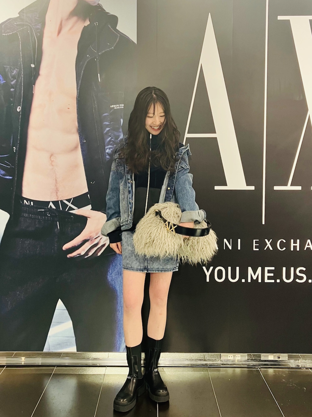 ブルー系のデニムジャケット、ブルー系のパーカー、ベージュ系のハンドバッグを着用したレディースの秋コーディネートの1枚目の写真