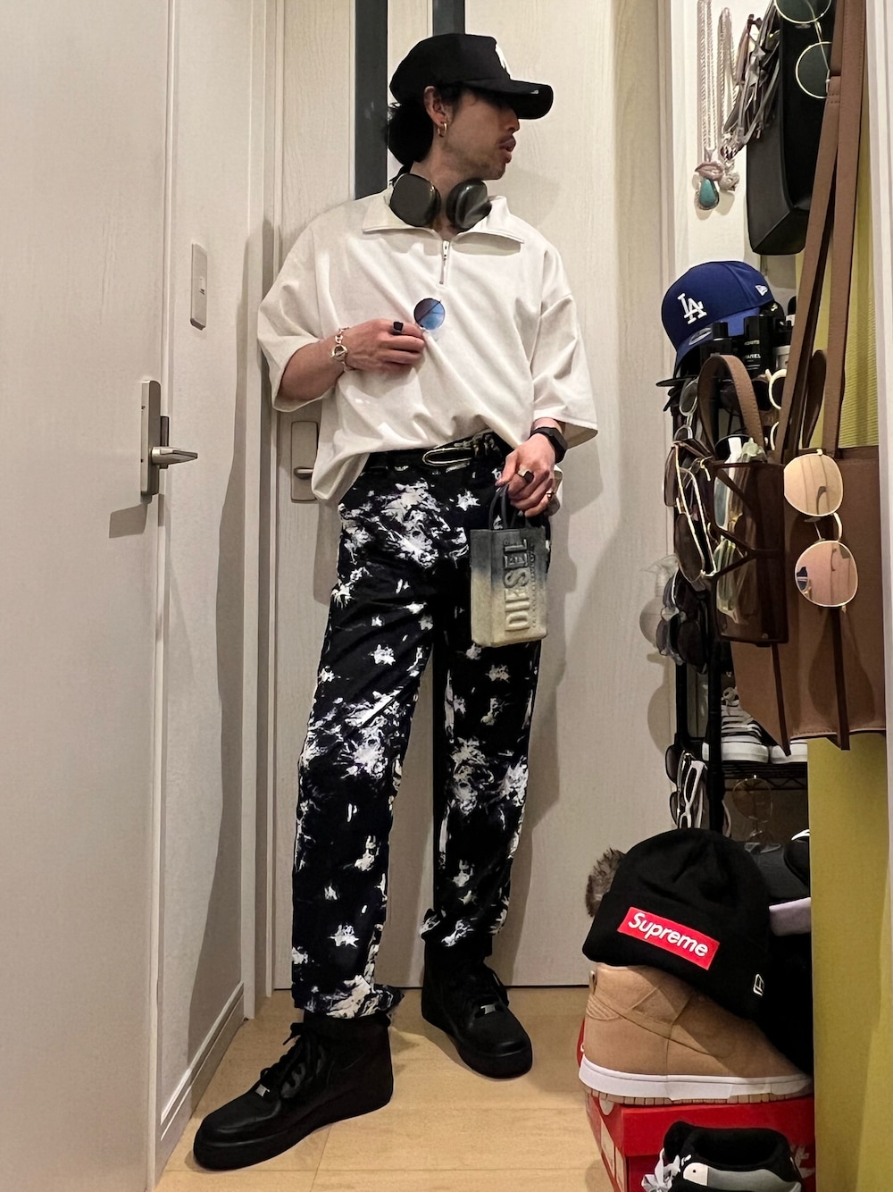 ブラック系のパンツ、ブラック系のスニーカー、ブルー系のショルダーバッグを着用したメンズの春コーディネートの1枚目の写真