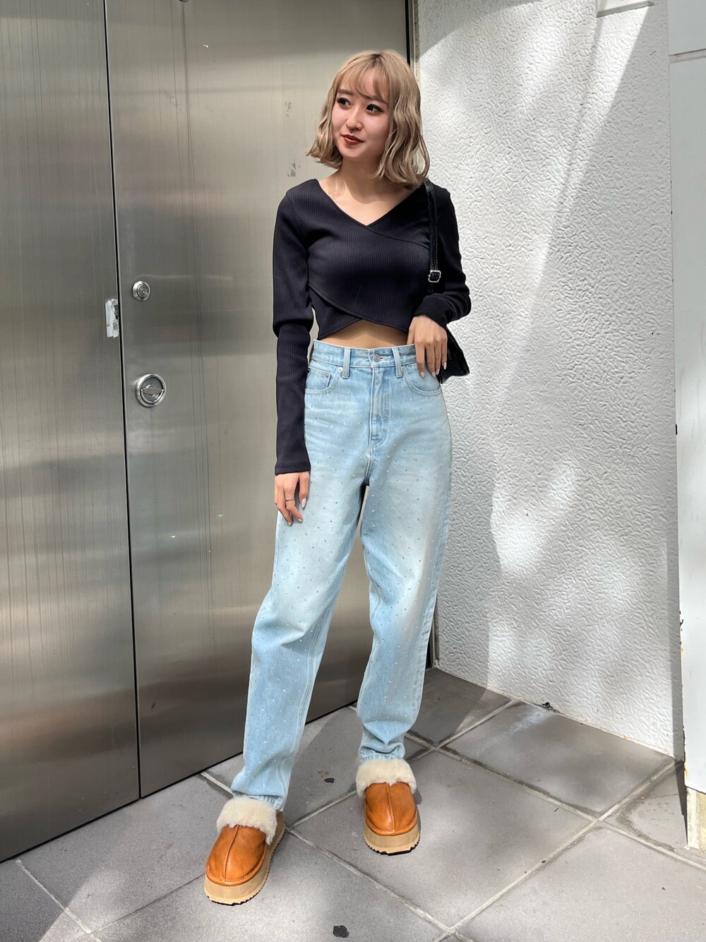 ブラック系のTシャツ/カットソー、ベージュ系のスリッポン、ブルー系のデニムパンツを着用したレディースの秋コーディネートの1枚目の写真