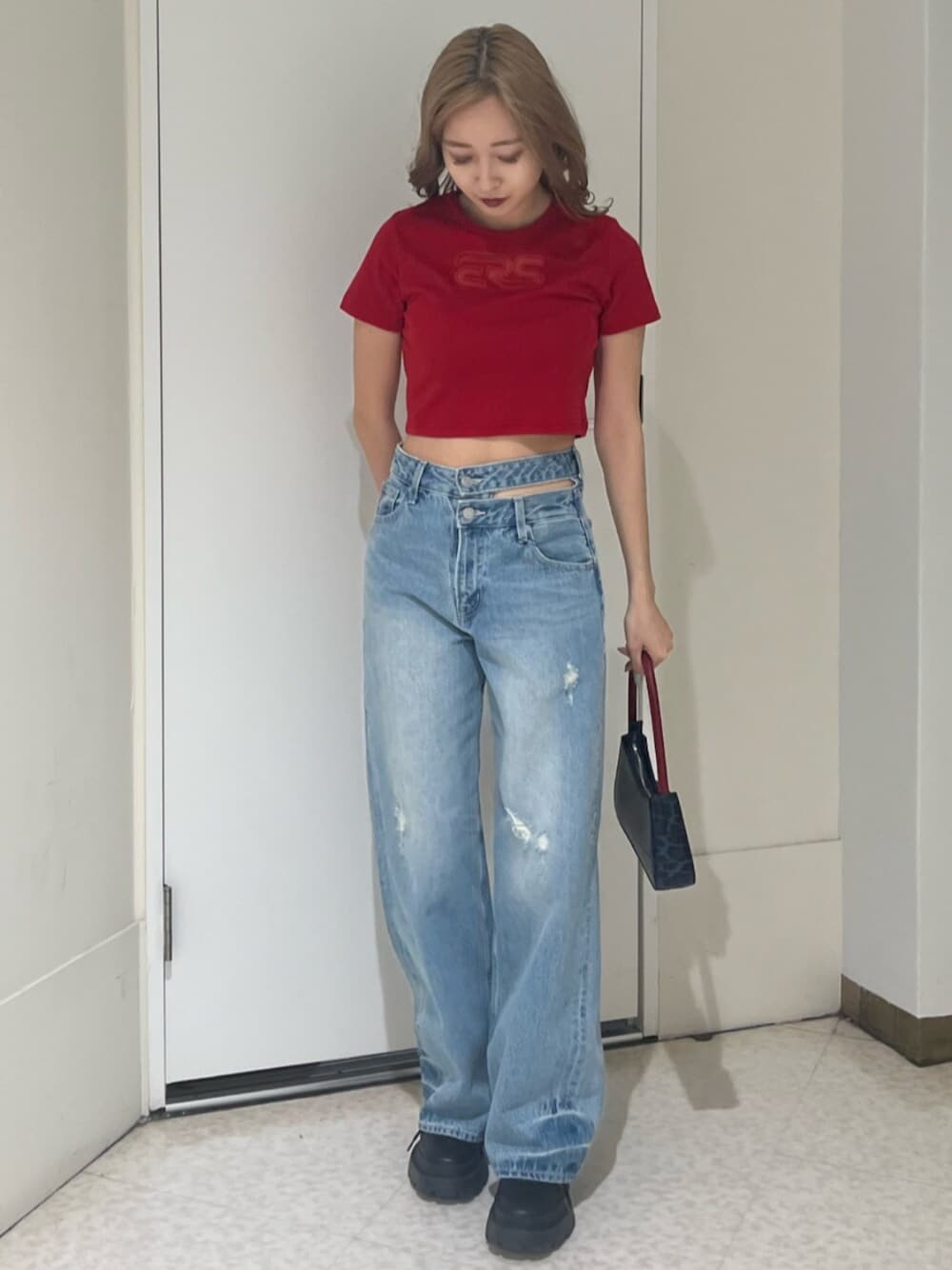 ブラック系のブーツ、ブラウン系のハンドバッグ、ブルー系のデニムパンツを着用したレディースの春コーディネートの1枚目の写真