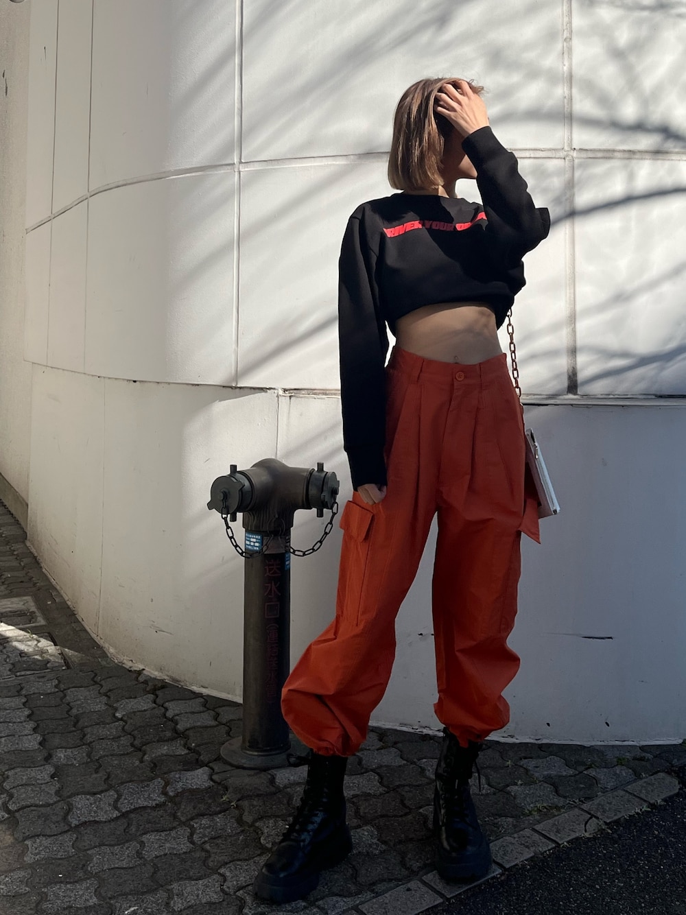 オレンジ系のカーゴパンツ、ホワイト系のブーツ、ブラック系のTシャツ/カットソーを着用したレディースの冬コーディネートの1枚目の写真