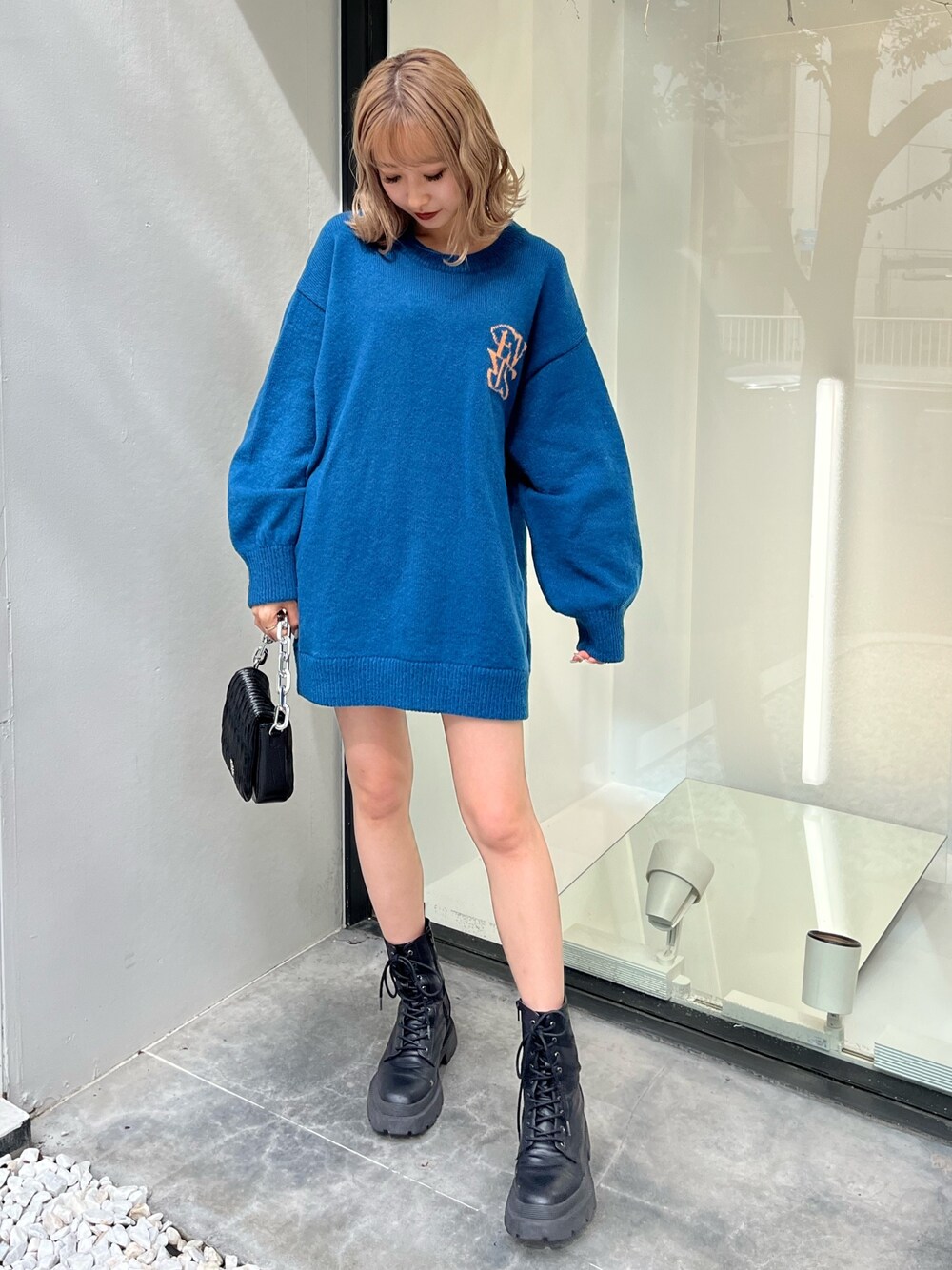 シルバー系のショルダーバッグ、ホワイト系のブーツ、ブルー系のニット/セーターを着用したレディースの秋コーディネートの1枚目の写真