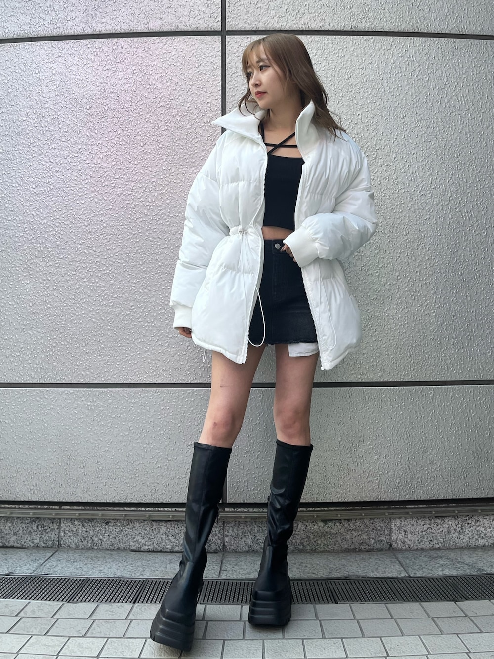 ブラック系のデニムスカート、ブラック系のTシャツ/カットソー、ブラック系のブーツを着用したレディースの冬コーディネートの1枚目の写真