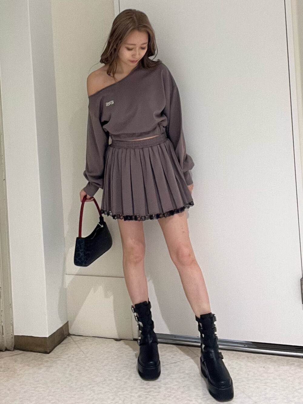 ブラック系のスウェット、ブラック系のスカート、ブラウン系のハンドバッグを着用したレディースの春コーディネートの1枚目の写真