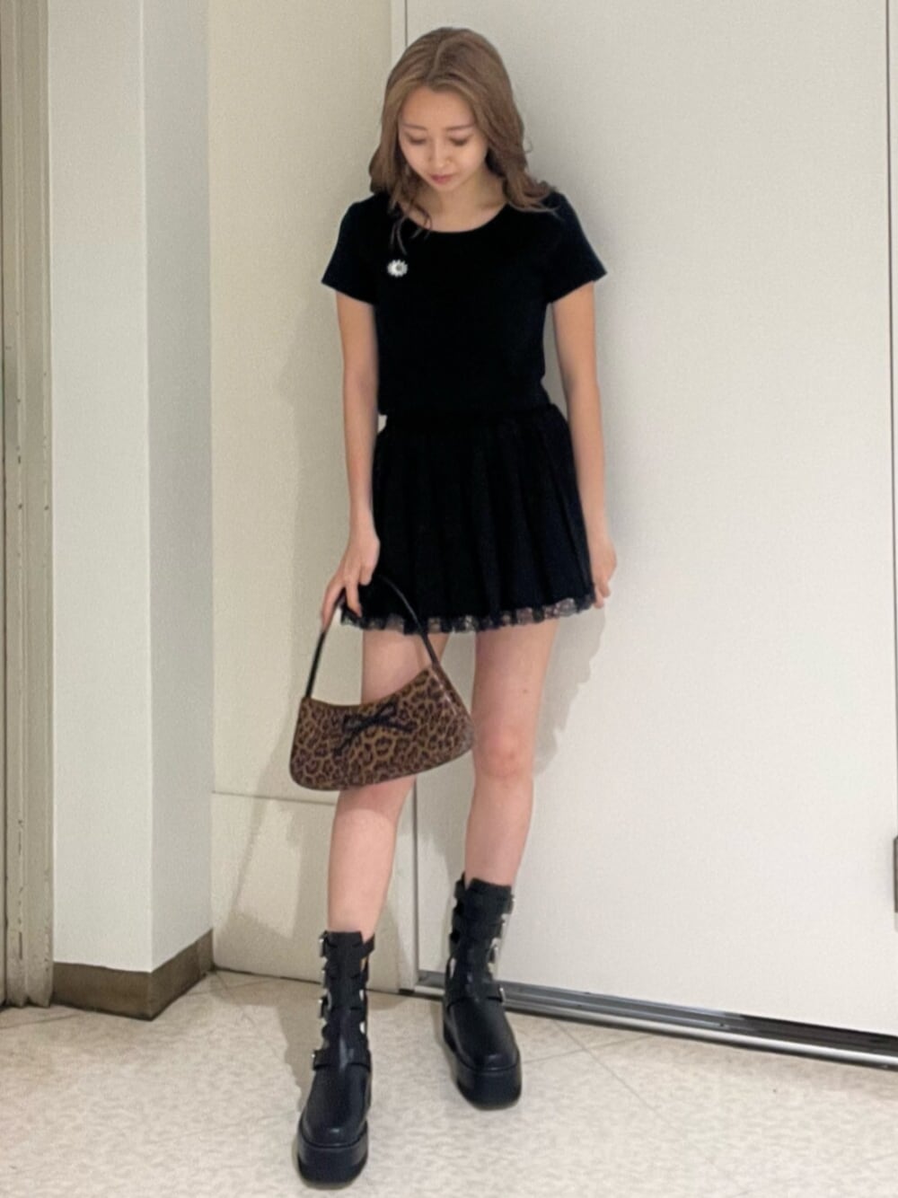 ブラウン系のハンドバッグ、ホワイト系のTシャツ/カットソー、ブラック系のブーツを着用したレディースの春コーディネートの1枚目の写真