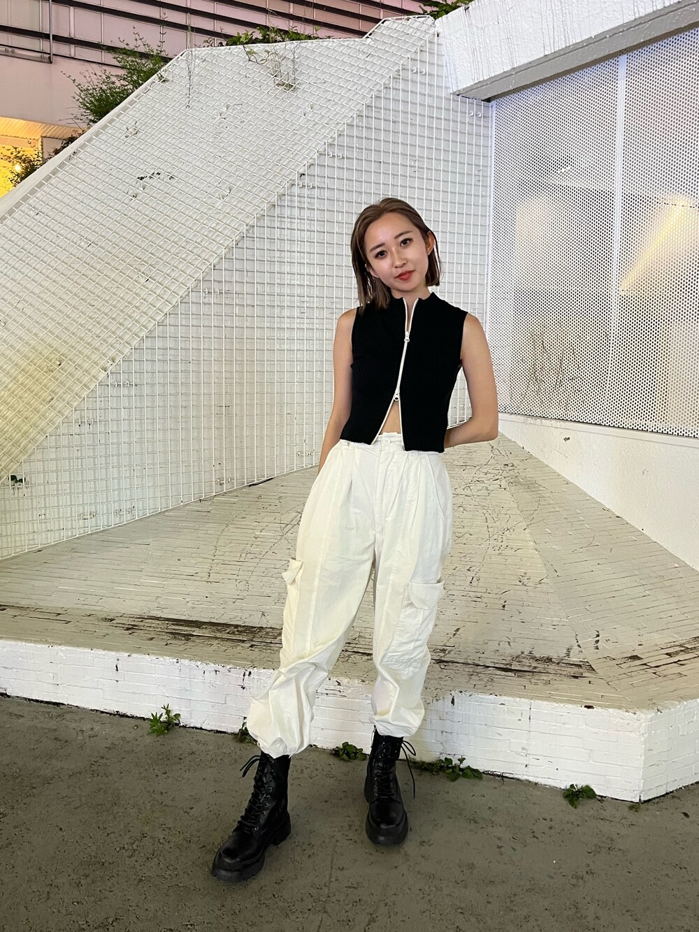 ホワイト系のカーゴパンツ、ブラック系のタンクトップ、ホワイト系のブーツを着用したレディースの夏コーディネートの1枚目の写真