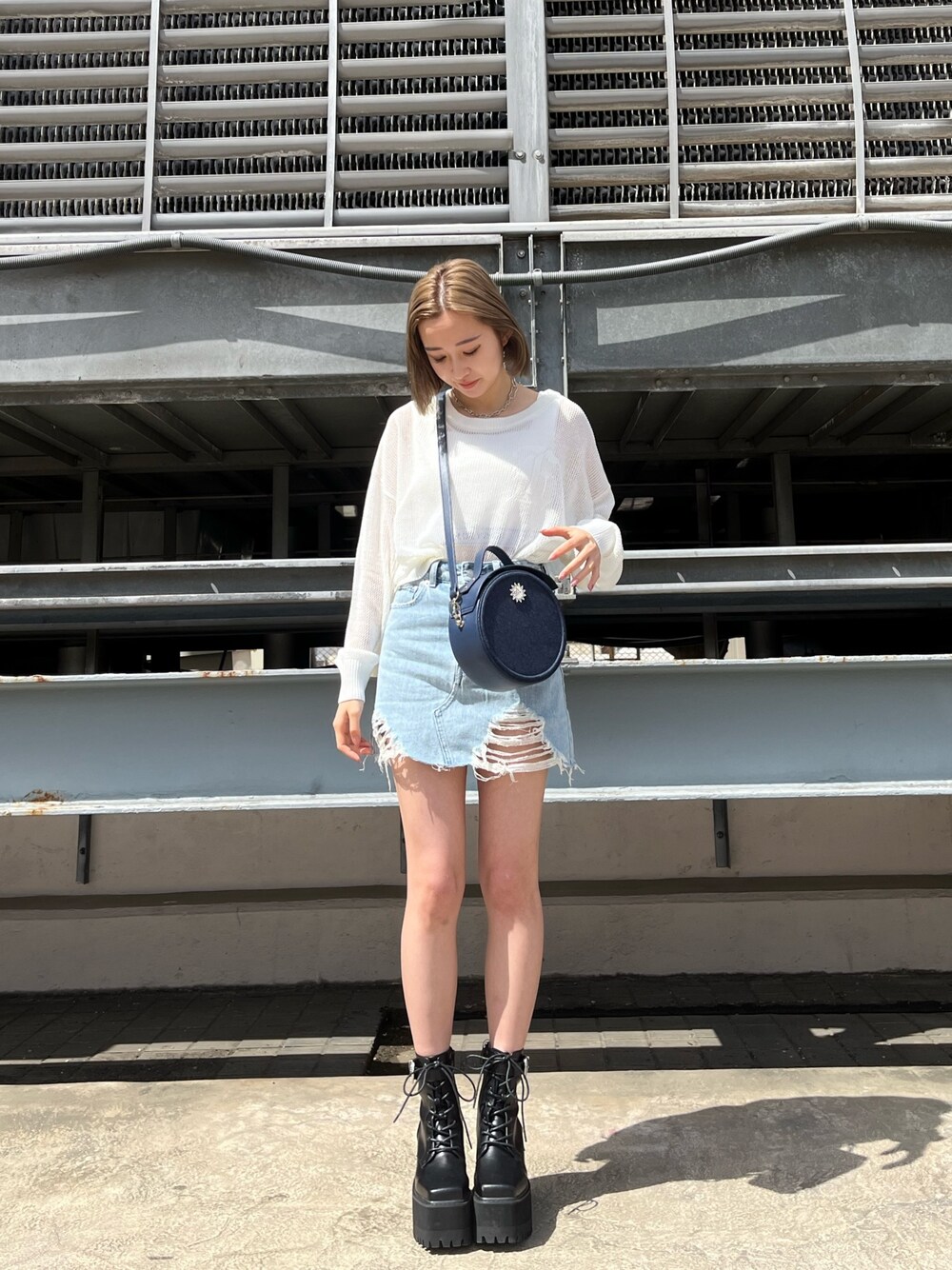 ブルー系のデニムスカート、ブラック系のブーツ、ブラック系のショルダーバッグを着用したレディースの春コーディネートの1枚目の写真