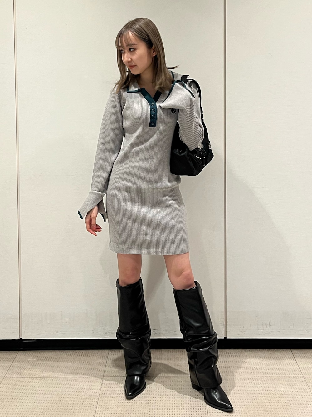 ブラック系のブーツ、グレー系のワンピース、ブラック系のハンドバッグを着用したレディースの冬コーディネートの1枚目の写真