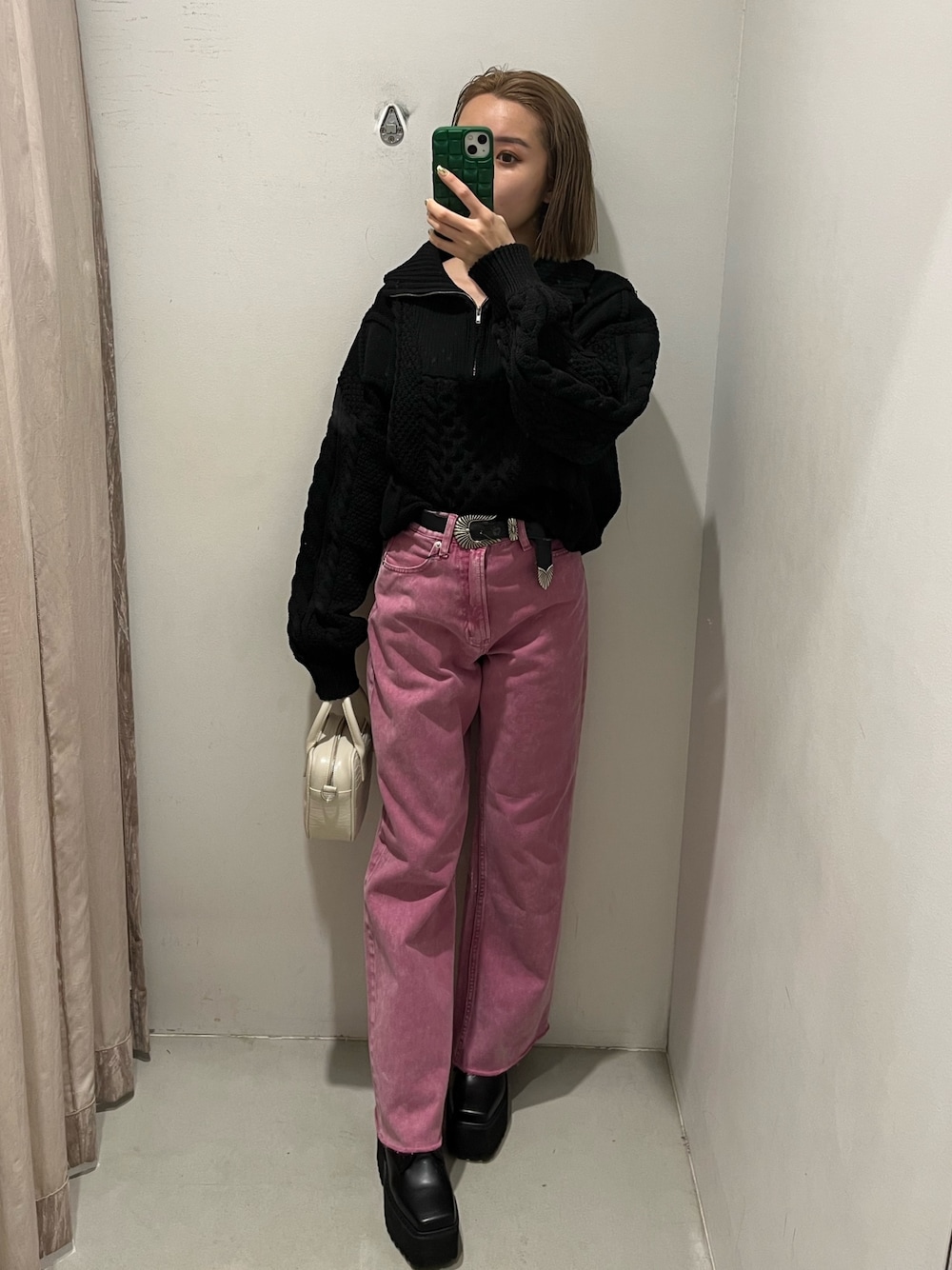 ピンク系のデニムパンツ、ブラック系のニット/セーター、ブルー系のショルダーバッグを着用したレディースの冬コーディネートの1枚目の写真