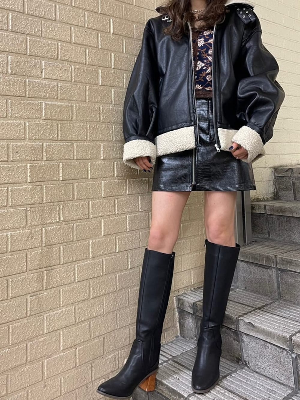 ブルー系のニット/セーター、ブラック系のブルゾン、ブラック系のブーツを着用したレディースの秋コーディネートの1枚目の写真