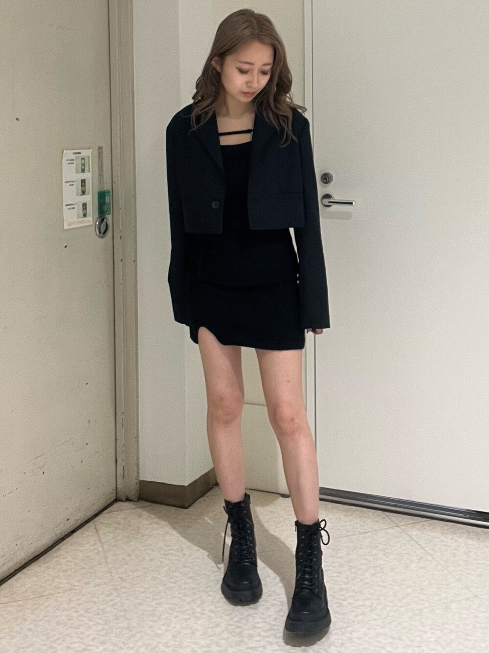 ブラック系のテーラードジャケット、ブラック系のワンピース、ブラック系のブーツを着用したレディースの春コーディネートの1枚目の写真