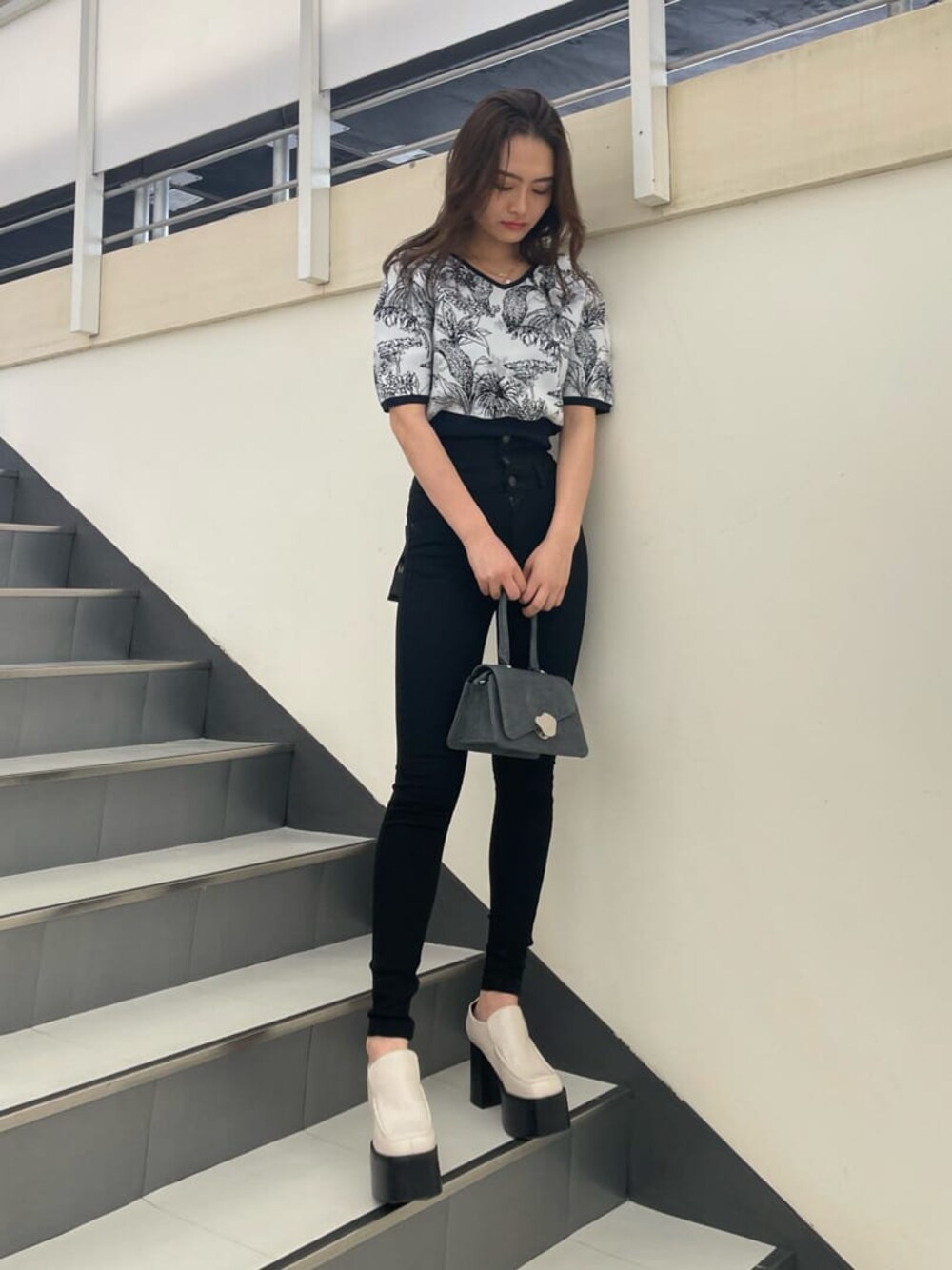 ホワイト系のローファー、ブラック系のハンドバッグ、ブラック系のデニムパンツを着用したレディースの春コーディネートの1枚目の写真