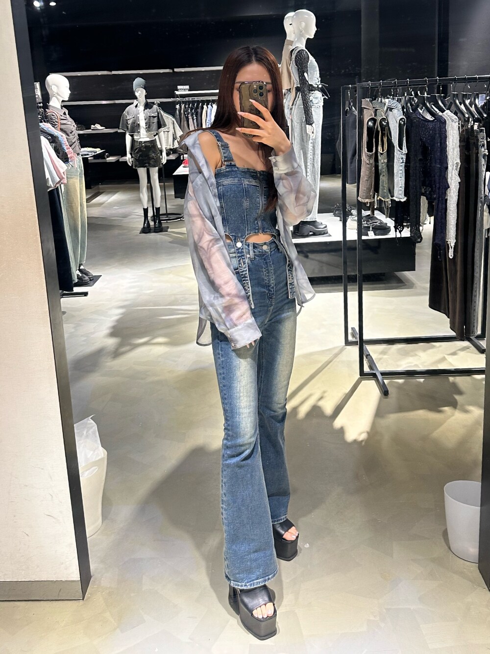 グレー系のシャツ/ブラウス、ブルー系のサロペット/オーバーオール、ブラック系のサンダルを着用したレディースの春コーディネートの1枚目の写真
