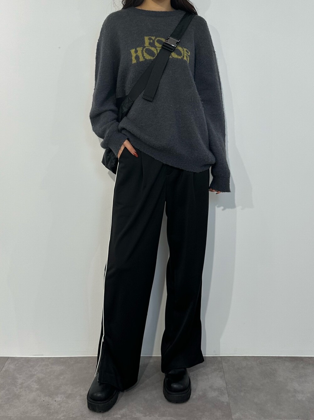 ブルー系のニット/セーター、ブラック系のスラックス、ブラック系のブーツを着用したレディースの冬コーディネートの1枚目の写真