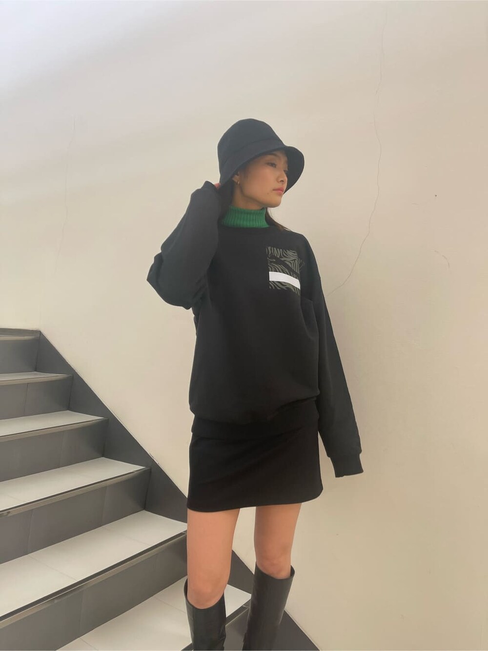 ブラック系のブーツ、ブラック系のTシャツ/カットソー、ブラック系のスカートを着用したレディースの冬コーディネートの1枚目の写真