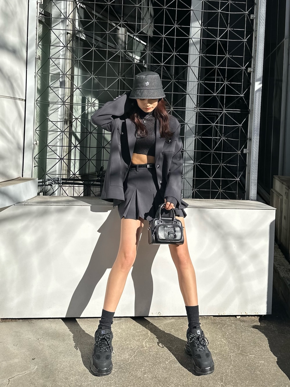 グレー系のスカート、ブラック系のスニーカー、その他のニット/セーターを着用したレディースの冬コーディネートの1枚目の写真