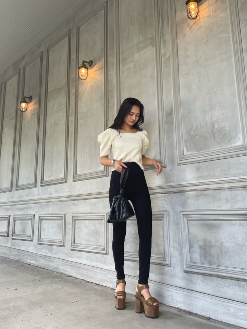 ブラック系のハンドバッグ、ブラウン系のサンダル、ホワイト系のTシャツ/カットソーを着用したレディースの夏コーディネートの1枚目の写真