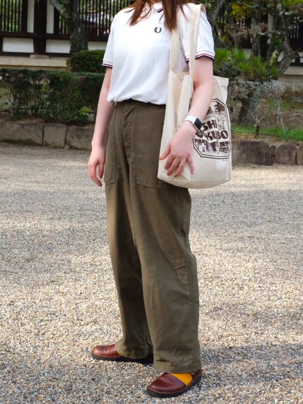 ホワイト系のポロシャツ、グリーン系のその他パンツ、ブラウン系のサンダルを着用したレディースの秋コーディネートの1枚目の写真
