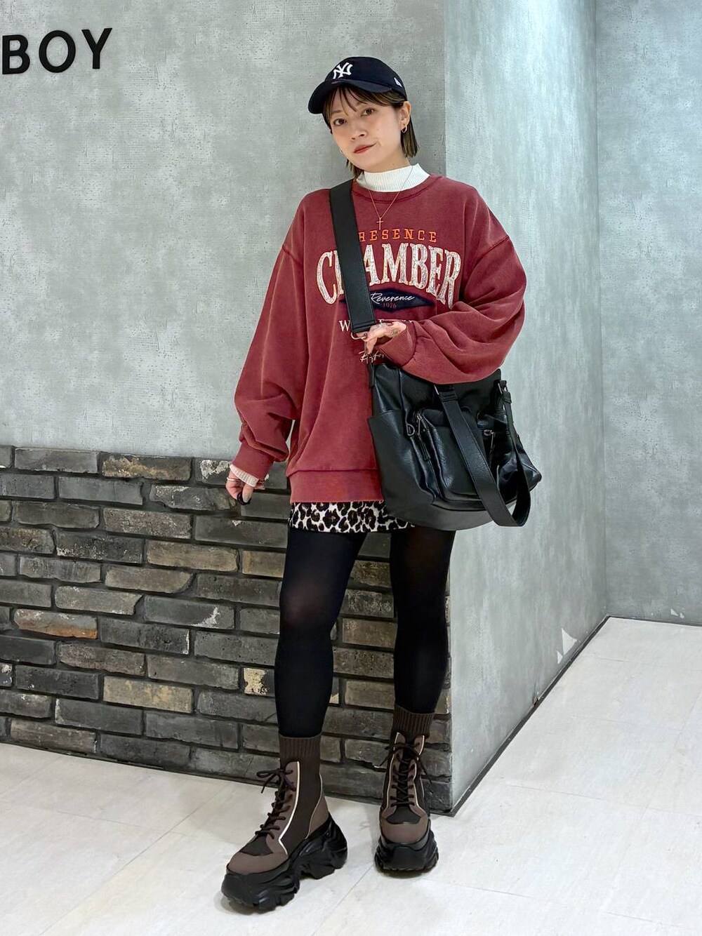 ブラウン系のブーツ、ブラック系のボストンバッグ、レッド系のスウェットを着用したレディースの冬コーディネートの1枚目の写真