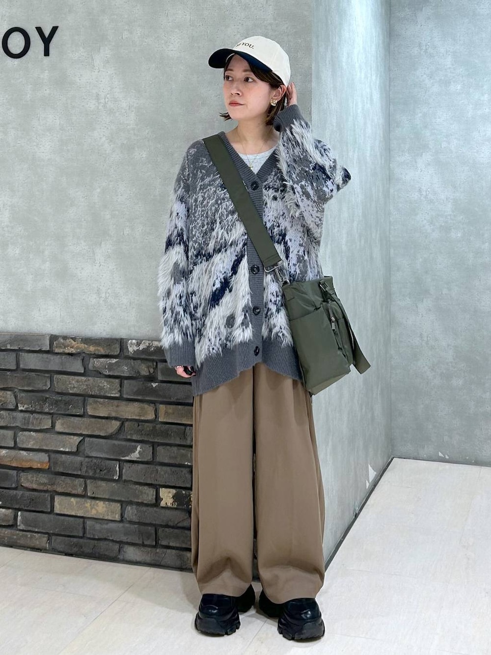 ブラック系のスニーカー、グリーン系のボストンバッグ、グレー系のカーディガン/ボレロを着用したレディースの秋コーディネートの1枚目の写真