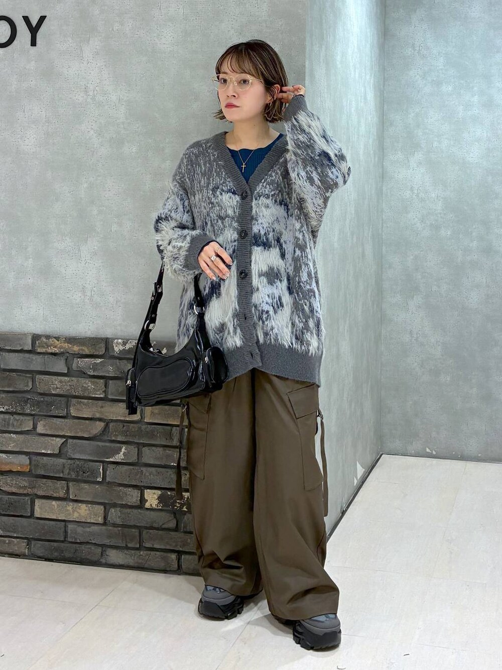 グレー系のスニーカー、ブラウン系のスラックス、グリーン系のニット/セーターを着用したレディースの冬コーディネートの1枚目の写真