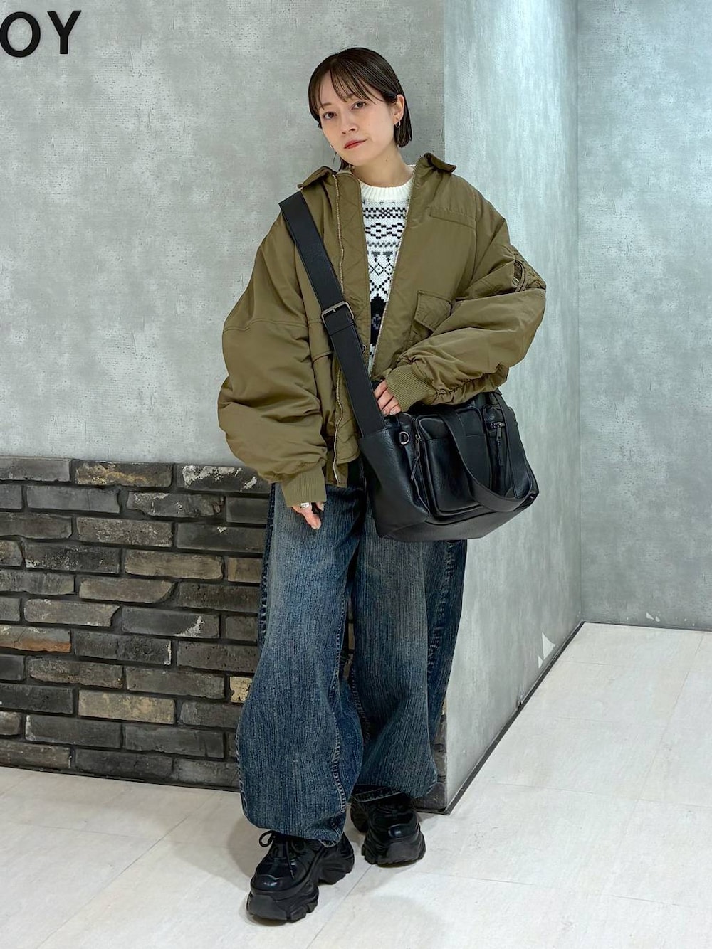 ブラック系のスニーカー、ブラック系のボストンバッグ、ブルー系のデニムパンツを着用したレディースの冬コーディネートの1枚目の写真