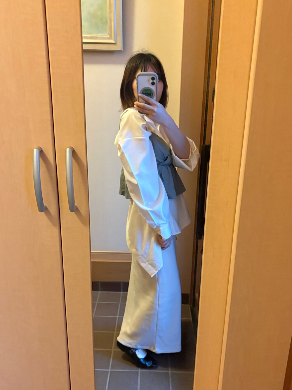 ブラック系のバレエシューズ、ホワイト系のスカート、ベージュ系のシャツ/ブラウスを着用したレディースの春コーディネートの1枚目の写真